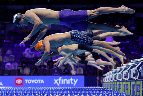 Swimmers dive into a pool at the 2021 U.S. Olympic Team Swimming Trials.